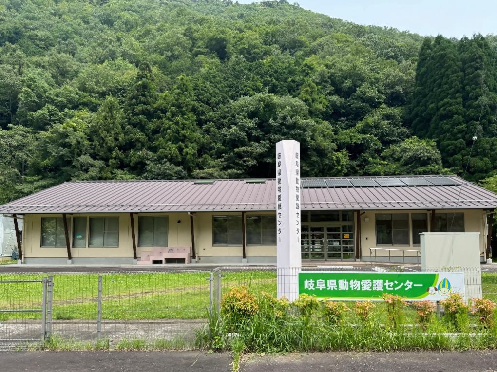 緑豊かな山々を背景に建つ岐阜県動物愛護センターの建物の外観と看板