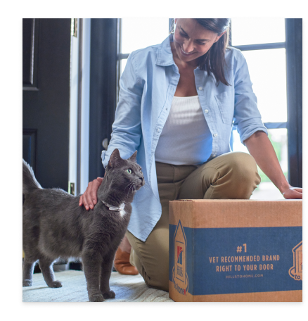 黒い毛並みの猫とヒルズのキャットフードパッケージと一緒にいる女性